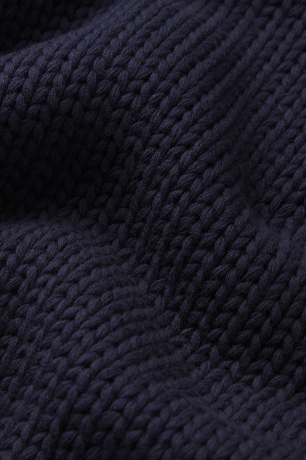 Close-up of the Jane Cotton Sweater in English Navy, showing dark blue, chunky knit with textured stitches and folds. Made from 100% cotton for classic craftsmanship and cozy comfort.