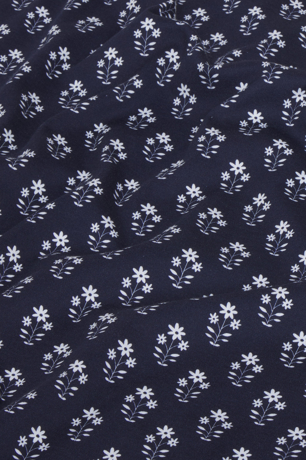 A detailed look at the Pima Long Sleeve Bundle in English Navy Posy, highlighting petite white bouquets and leaves on soft Pima cotton against a rich navy blue background.