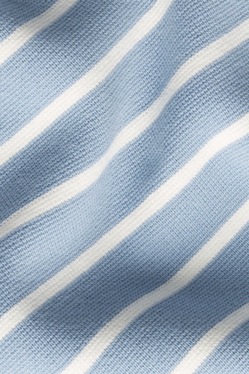 Close-up of the Lydia Cotton Sweater in Dusty Blue Ivory Stripe, showing white horizontal stripes and a soft knitted texture with gentle folds in 100% cotton fabric.