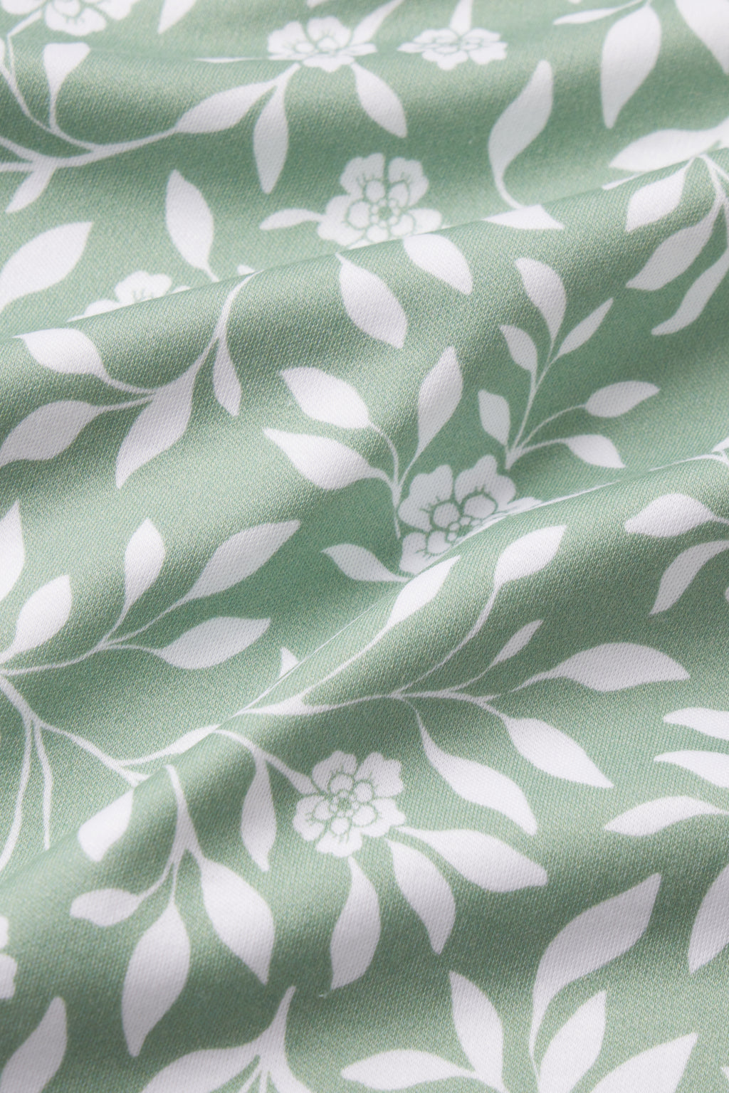 The Pima Nightgown in Granite Green Cecil Floral features soft green 100% Pima cotton with a white floral and leafy pattern. Small flowers, branches, gentle folds, and light shadows enhance its elegant look.