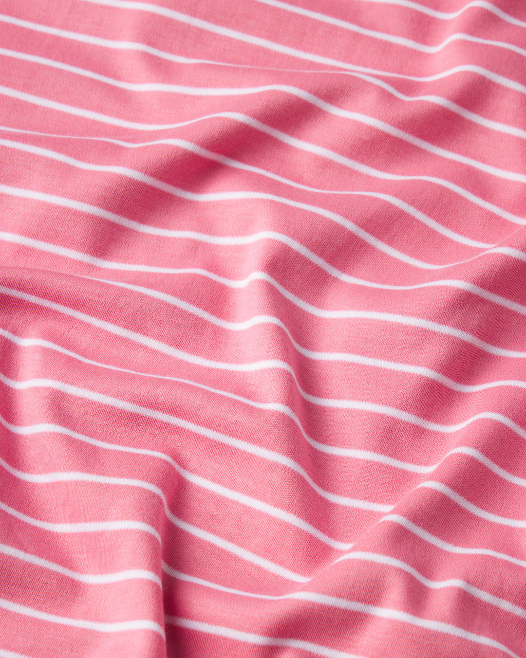 The Pima Nightgown in Sunkissed Coral Rowing Stripe is crafted from 100% Pima cotton, with thin white horizontal stripes, gentle folds, and a soft texture.