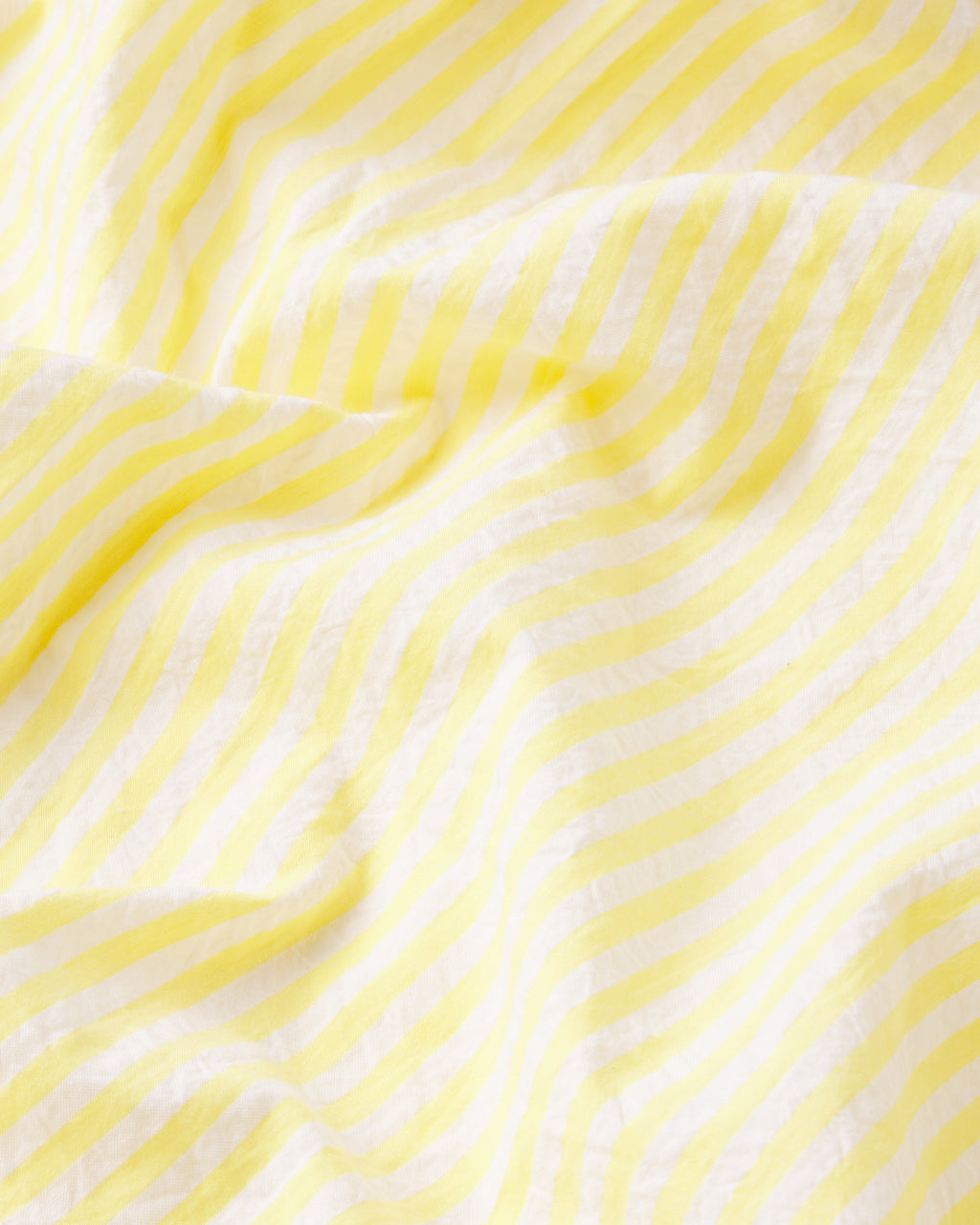 Close-up of the Alice Shorts Set in Zest Seersucker, showcasing yellow and white striped fabric with gentle folds and a softly crumpled texture.