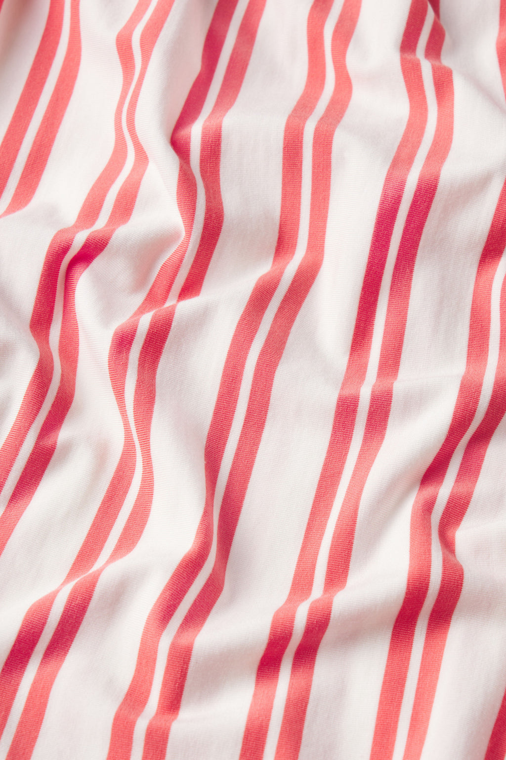 A close-up of the DreamModal Daydream Shorts Set in Terrace Stripe shows its soft white fabric with vertical wavy red stripes, creating gentle folds and shadows.