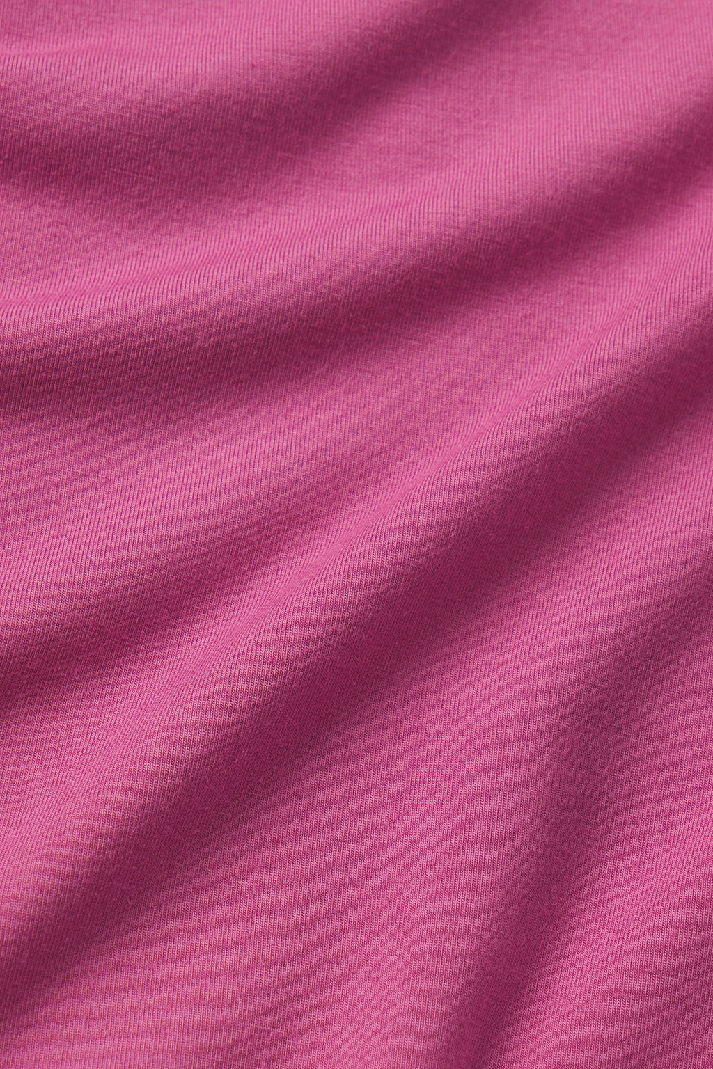 A close-up of the DreamModal Ribbon Long-Long Set in Camellia shows soft, pink finely ribbed fabric with subtle folds, making it perfect for cozy sleepwear or comfortable pajama pants.
