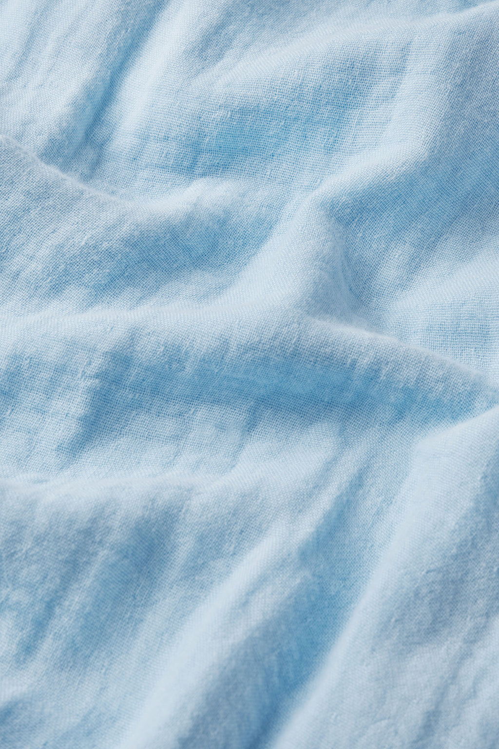 A close-up of soft, light blue cotton modal fabric with gentle folds—ideal for hot sleepers and featured in the Hamptons Nightgown in French Blue.