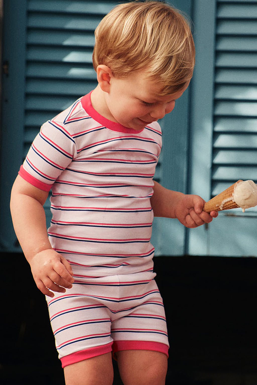Child wearing short-sleeved striped shirt and matching shorts in red, navy, and white horizontal stripes with solid red cuffs