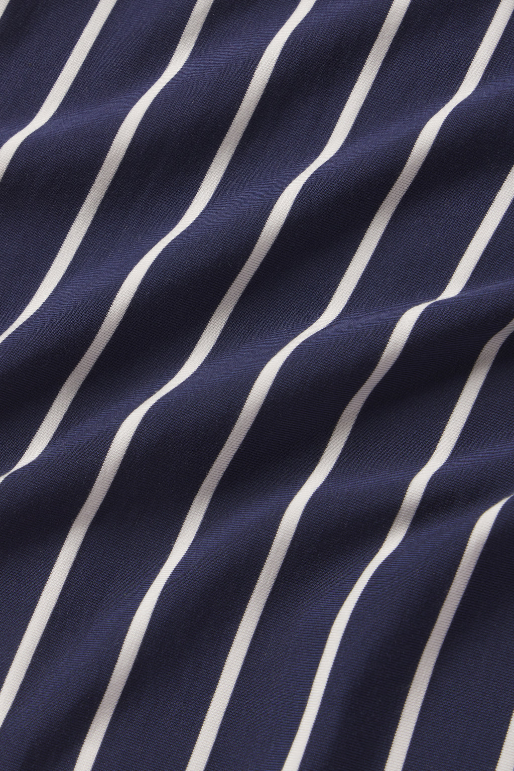 A close-up of the DreamModal Kimono Pajama Set in English Navy Vertical Stripe, showing navy fabric with evenly spaced vertical white stripes and gentle folds forming soft shadows.