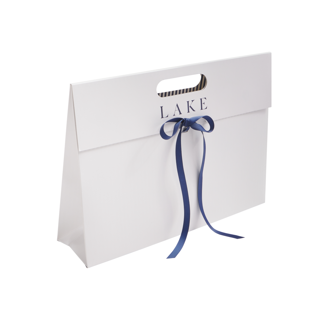 White self-assemble envelope with "LAKE" text, die-cut handles, and navy ribbon closure.