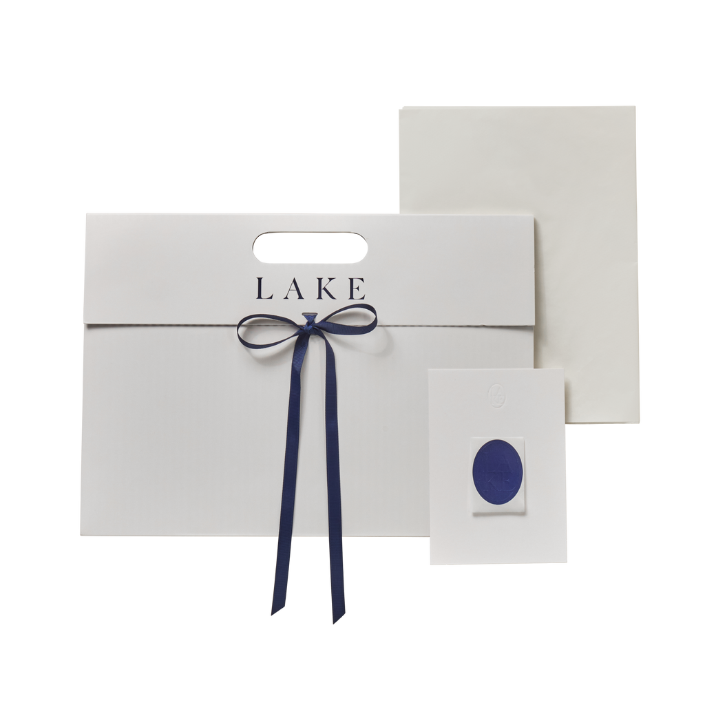 Flat-pack white envelope with handle, navy ribbon bow, and matching wax seal sticker.