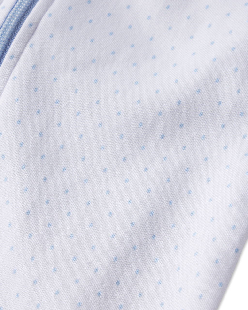 Close-up of the Baby Sleeper in French Blue Pindot, featuring soft white Pima cotton with evenly spaced light blue dots and a curved blue zipper on the left edge.
