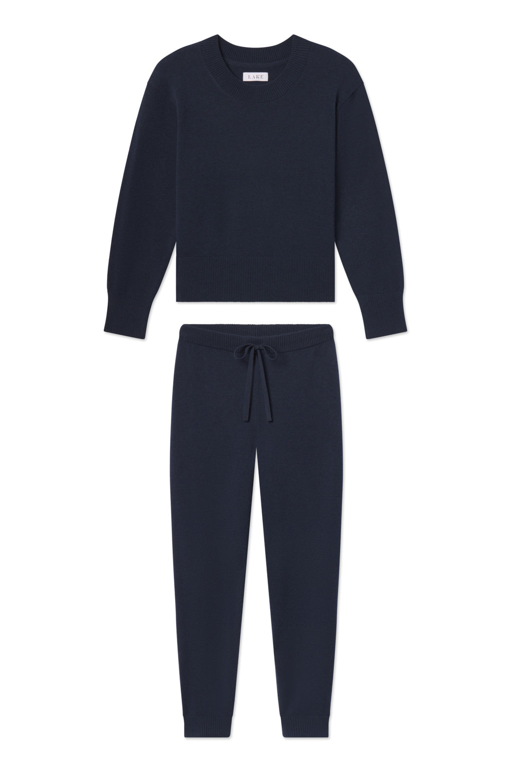 The Vesper Crew Neck Set in Deep Navy is a matching knit lounge set with a crewneck sweater and drawstring jogger pants, shown laid flat on a white background.