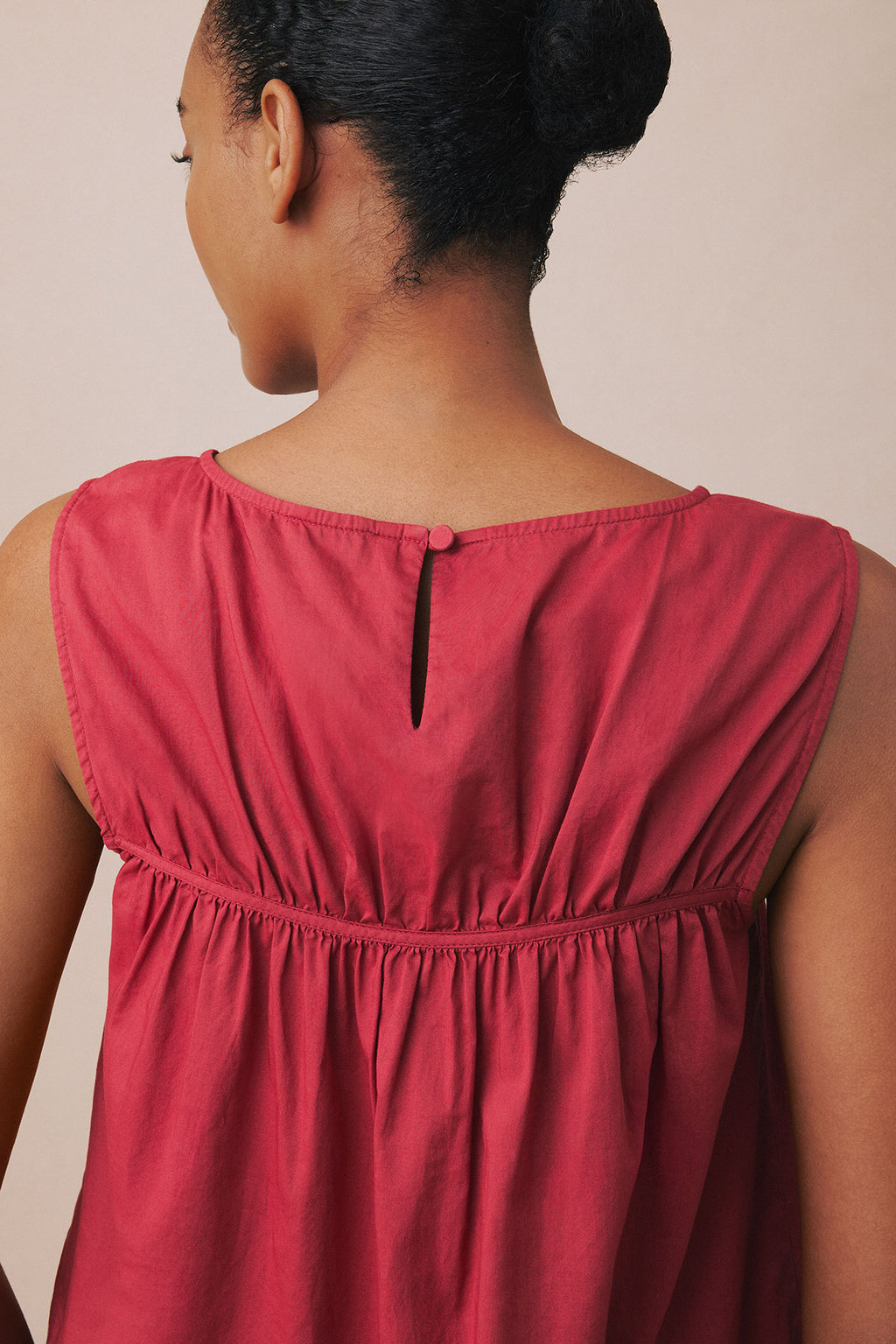 Burgundy sleeveless tank top with gathered waist detail and button back closure, shown from rear view.