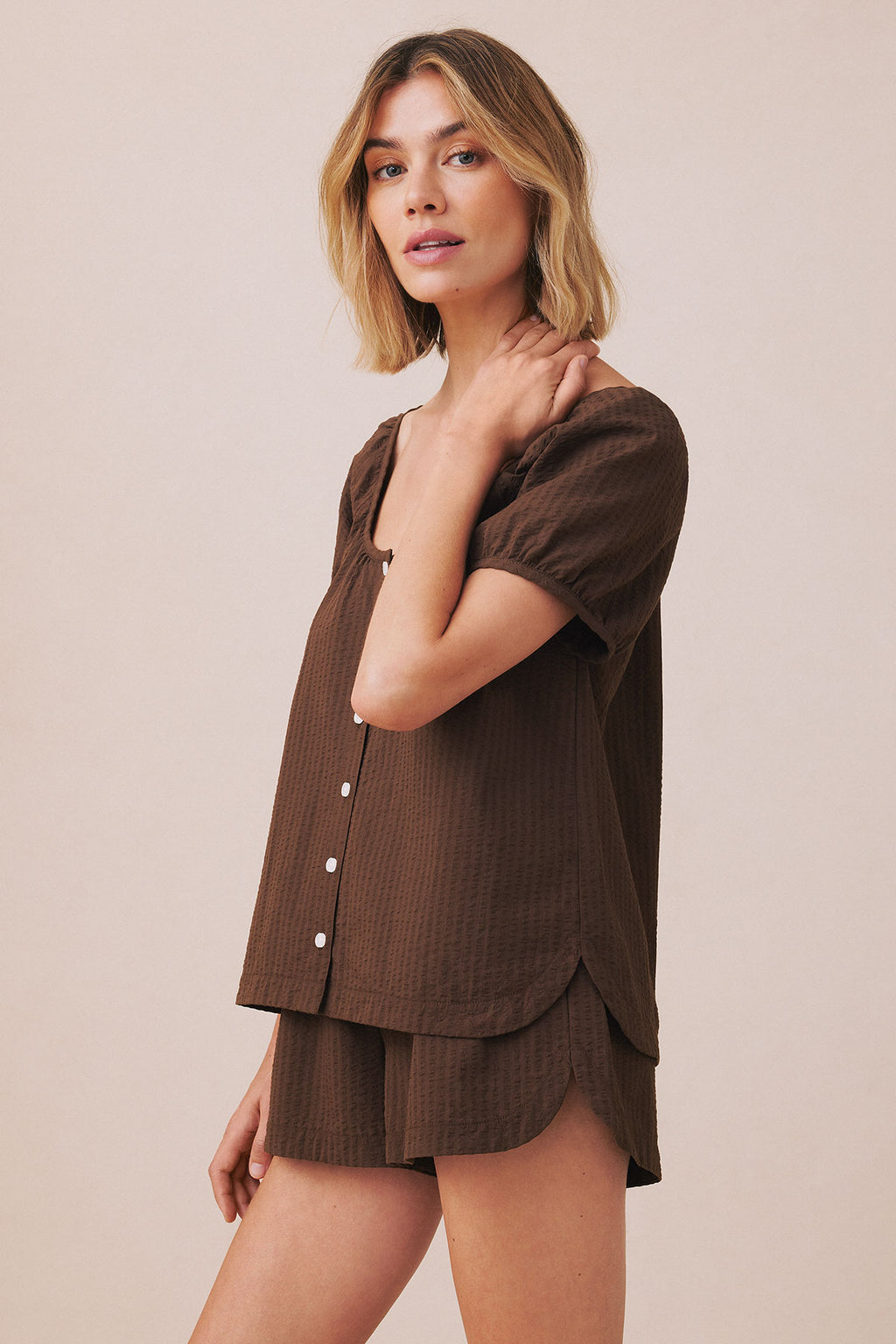 Woman wearing cocoa seersucker button-up shirt and matching shorts set.