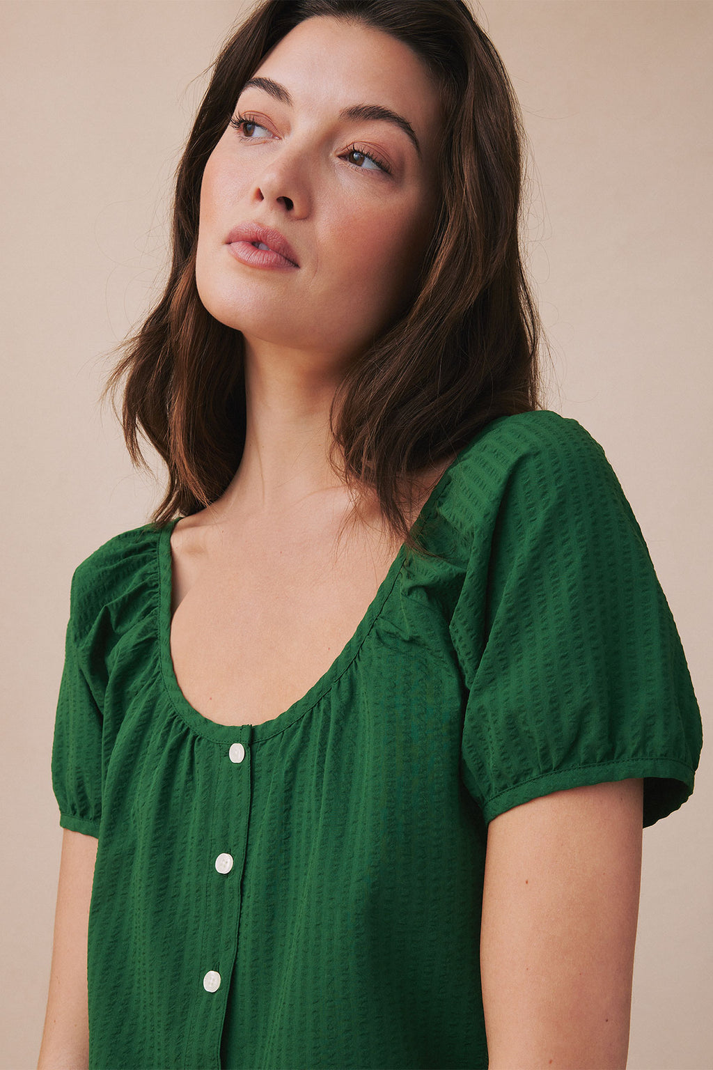 Green seersucker top with puffed short sleeves, V-neckline, and white button front closure.