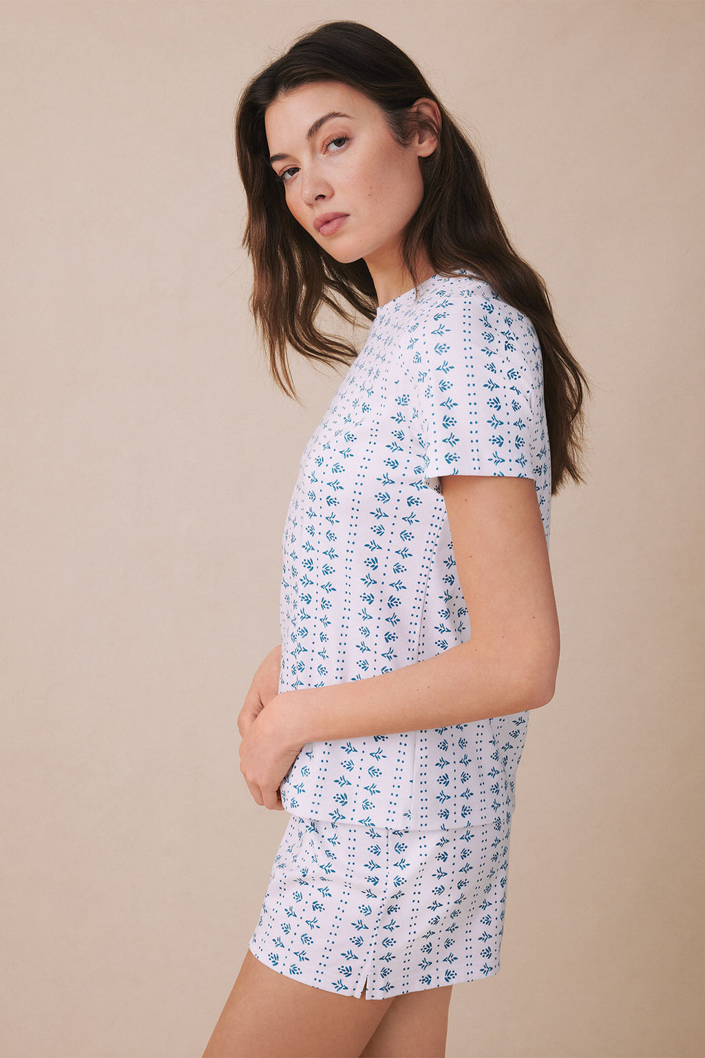 Woman wearing light blue crew neck shorts set with small blue floral and dot pattern.