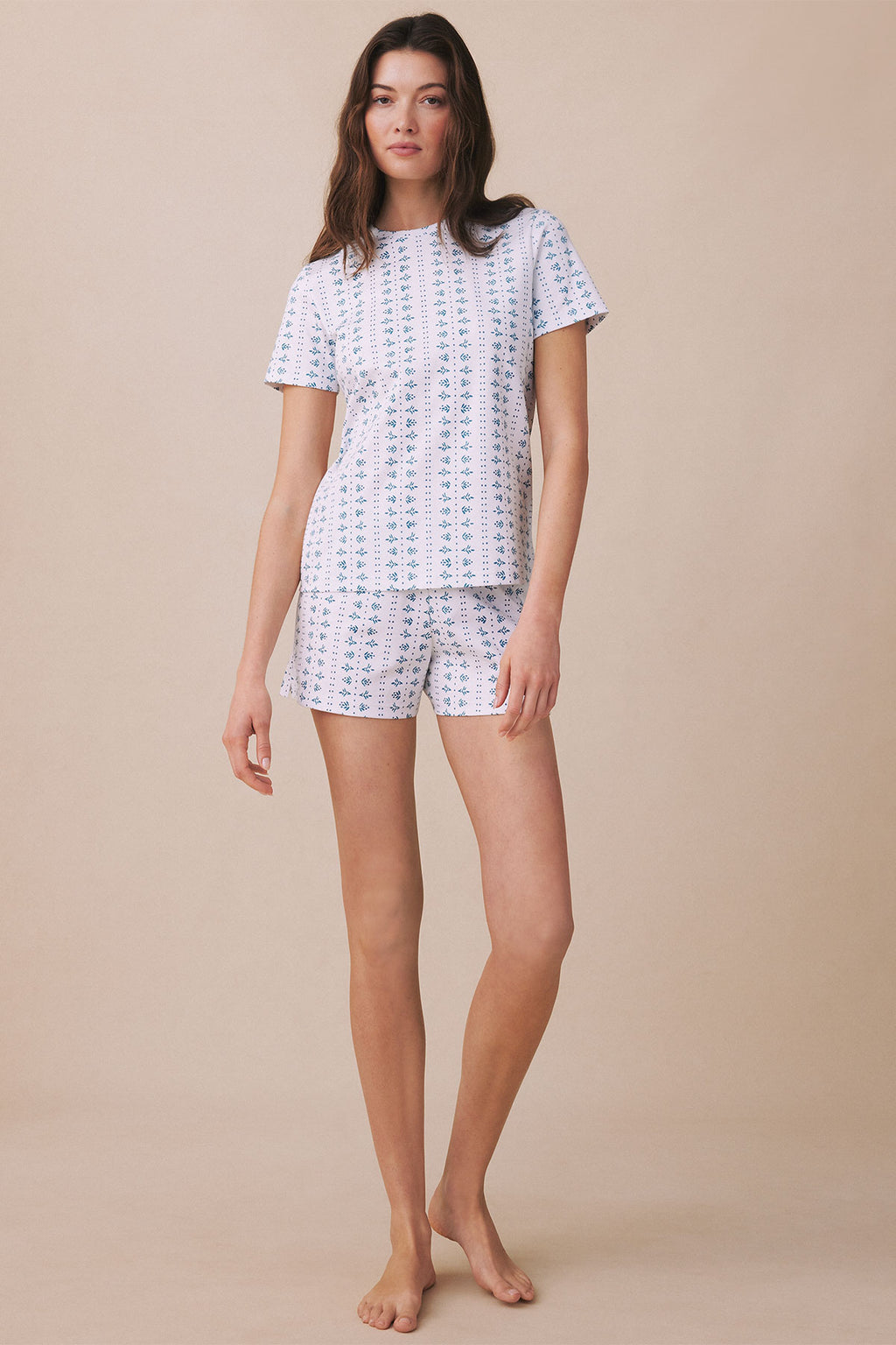 Woman wearing white short-sleeve crew neck shirt and matching shorts with blue geometric pattern.