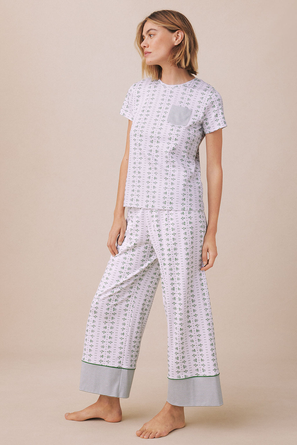 Woman wearing lavender floral pajama set with short-sleeve top and wide-leg pants with striped cuffs.