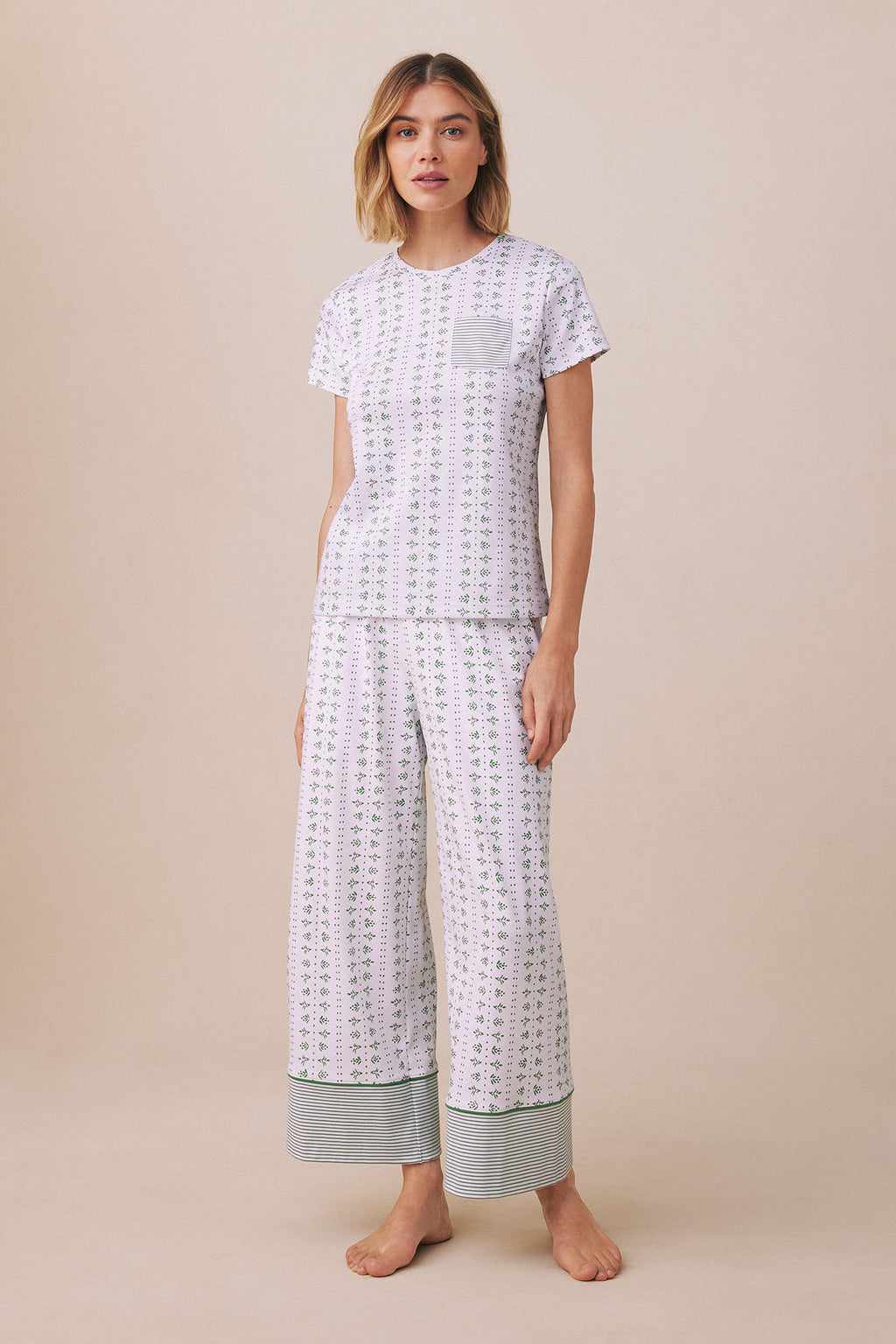 Woman wearing lavender patterned short-sleeve top and wide-leg pants with striped cuffs.