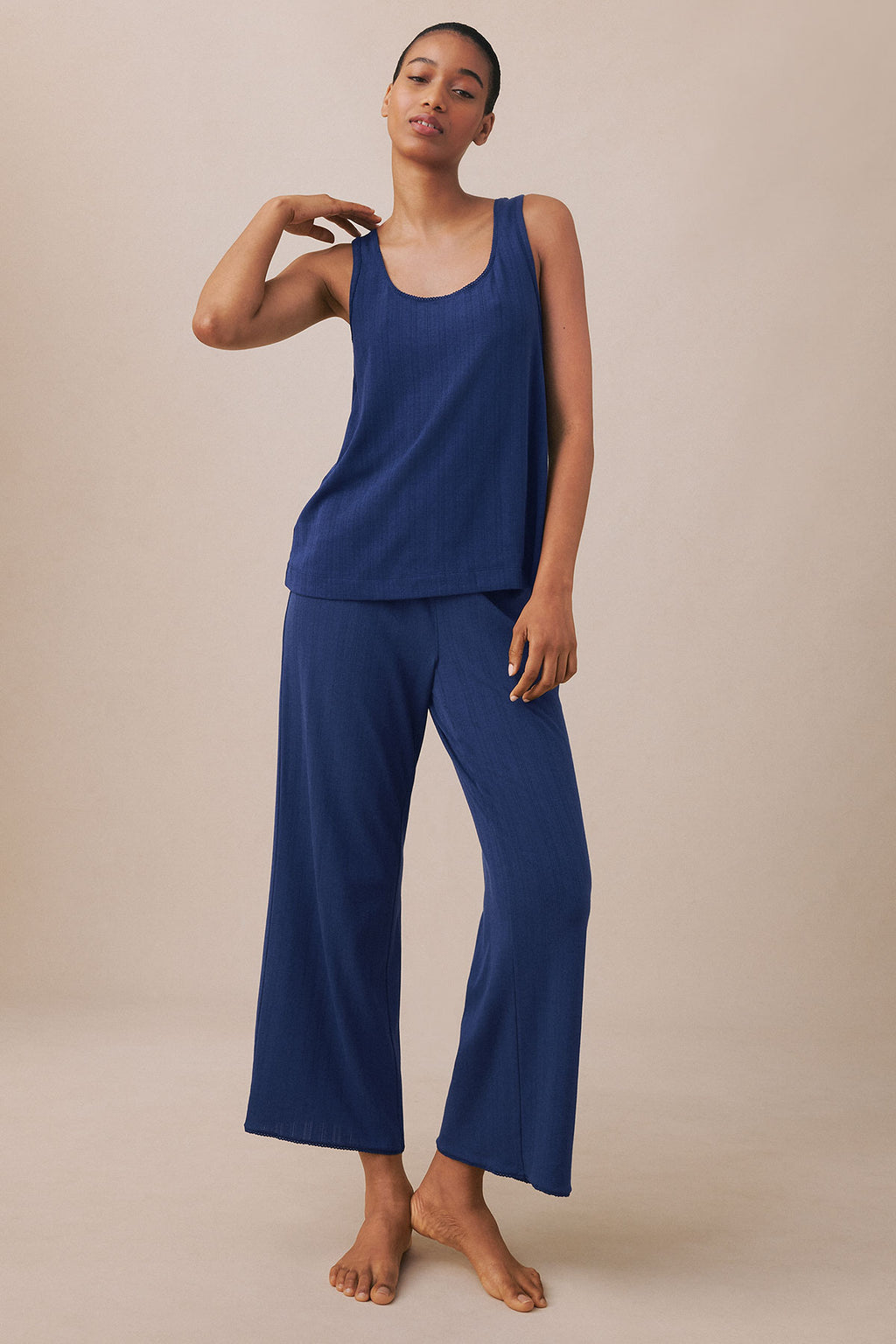 Woman wearing a dark blue sleeveless tank top and matching cropped wide-leg pants in pointelle knit fabric.