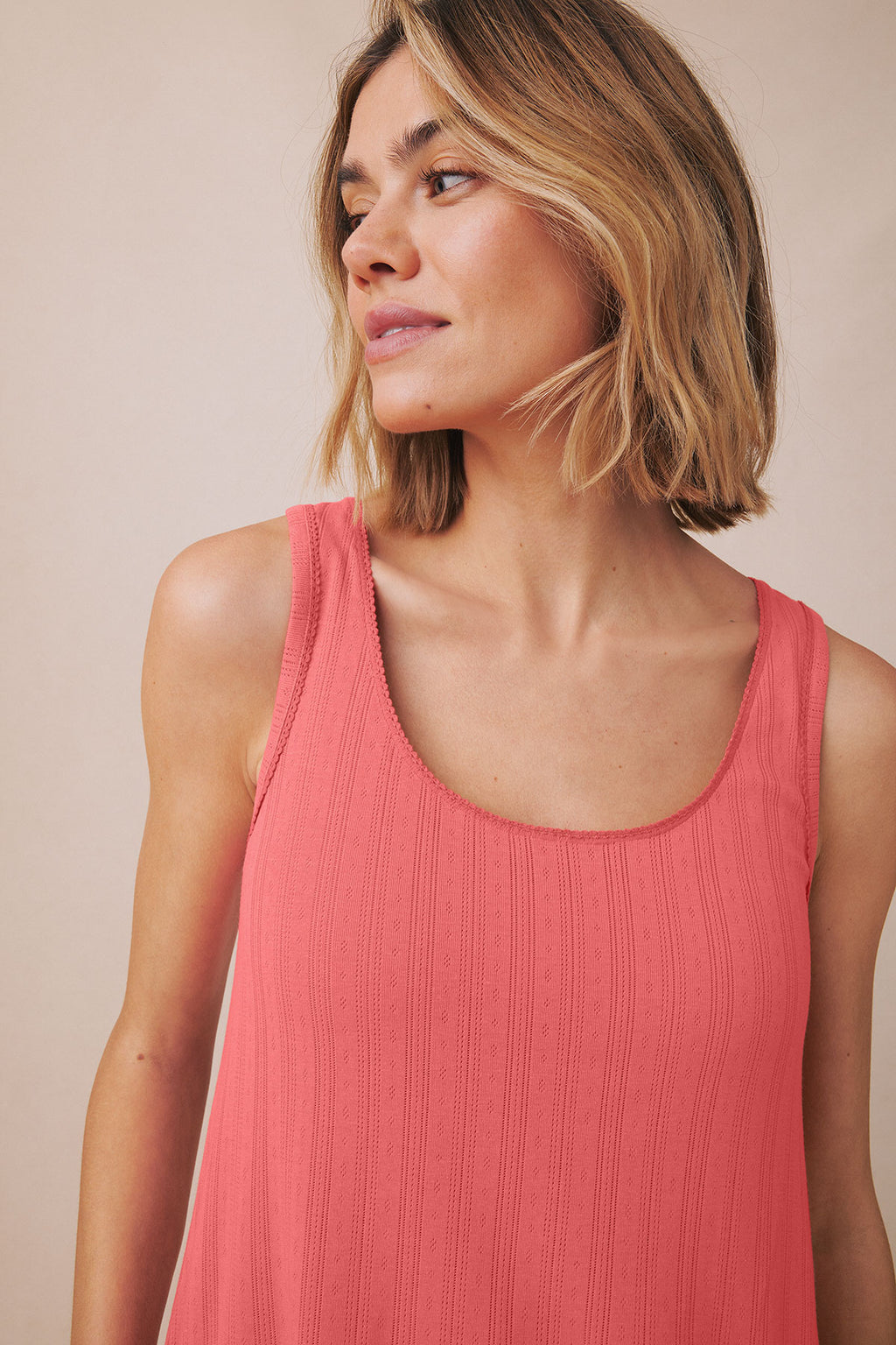 Coral-pink pointelle tank top with vertical ribbed texture and scoop neckline.