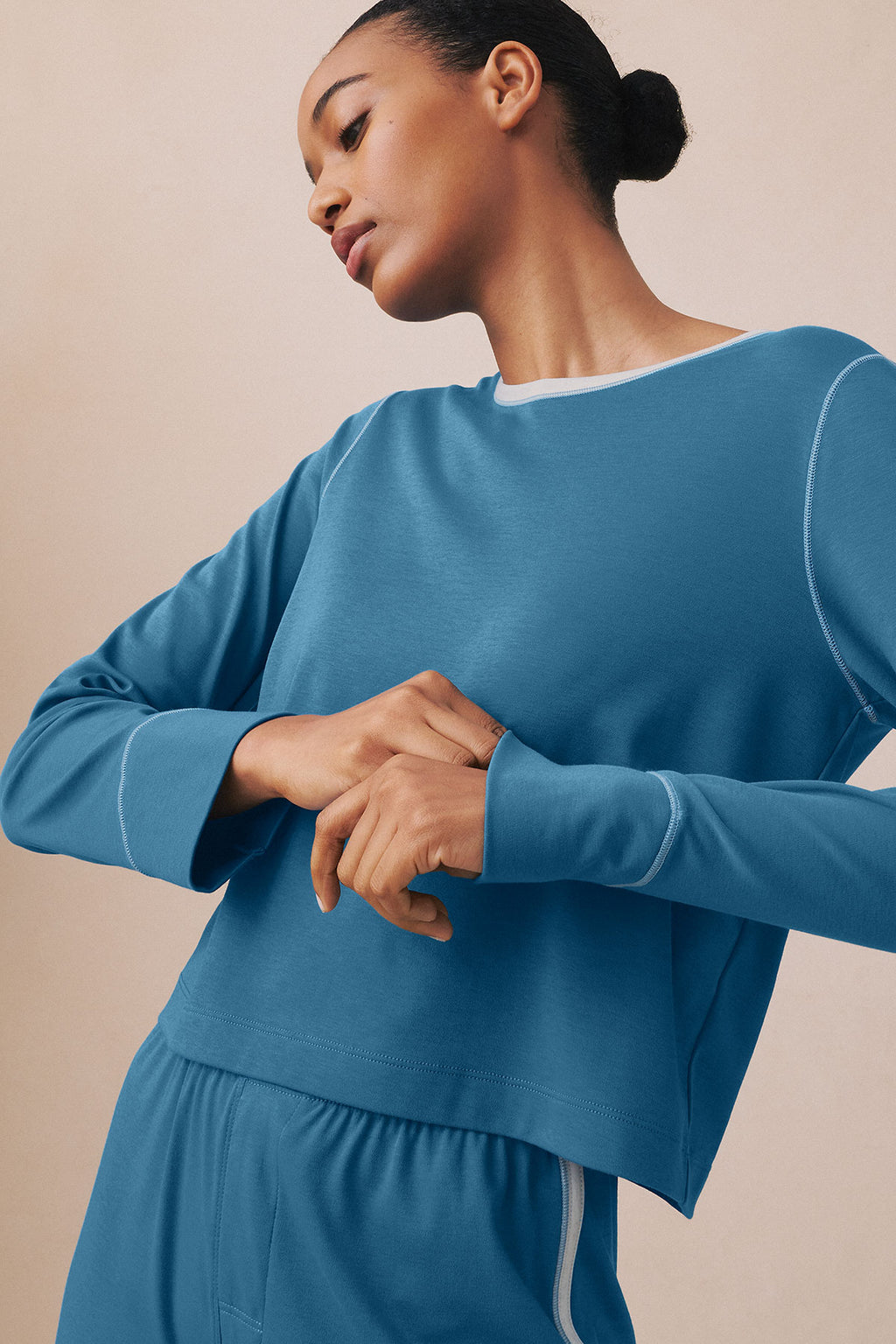 Woman wearing a blue long-sleeve knit top and matching pants with contrast stitching details.