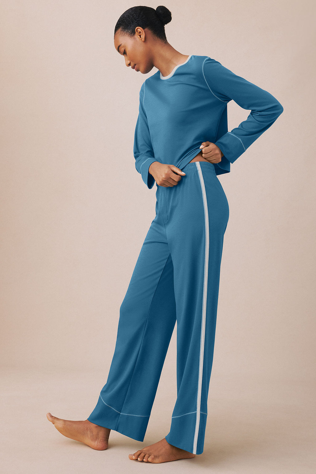 Woman wearing blue long-sleeve top and matching wide-leg pants with side stripe detail.