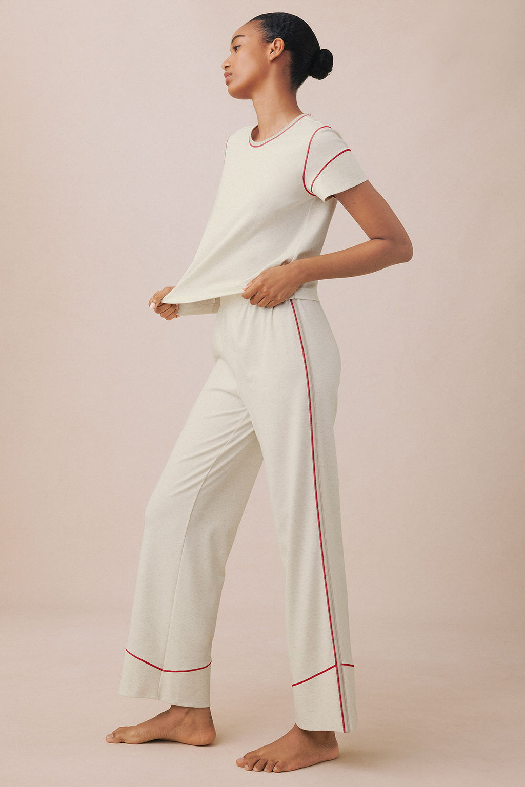 Woman wearing stone heather short-sleeve tee and matching long pants with red trim piping details.