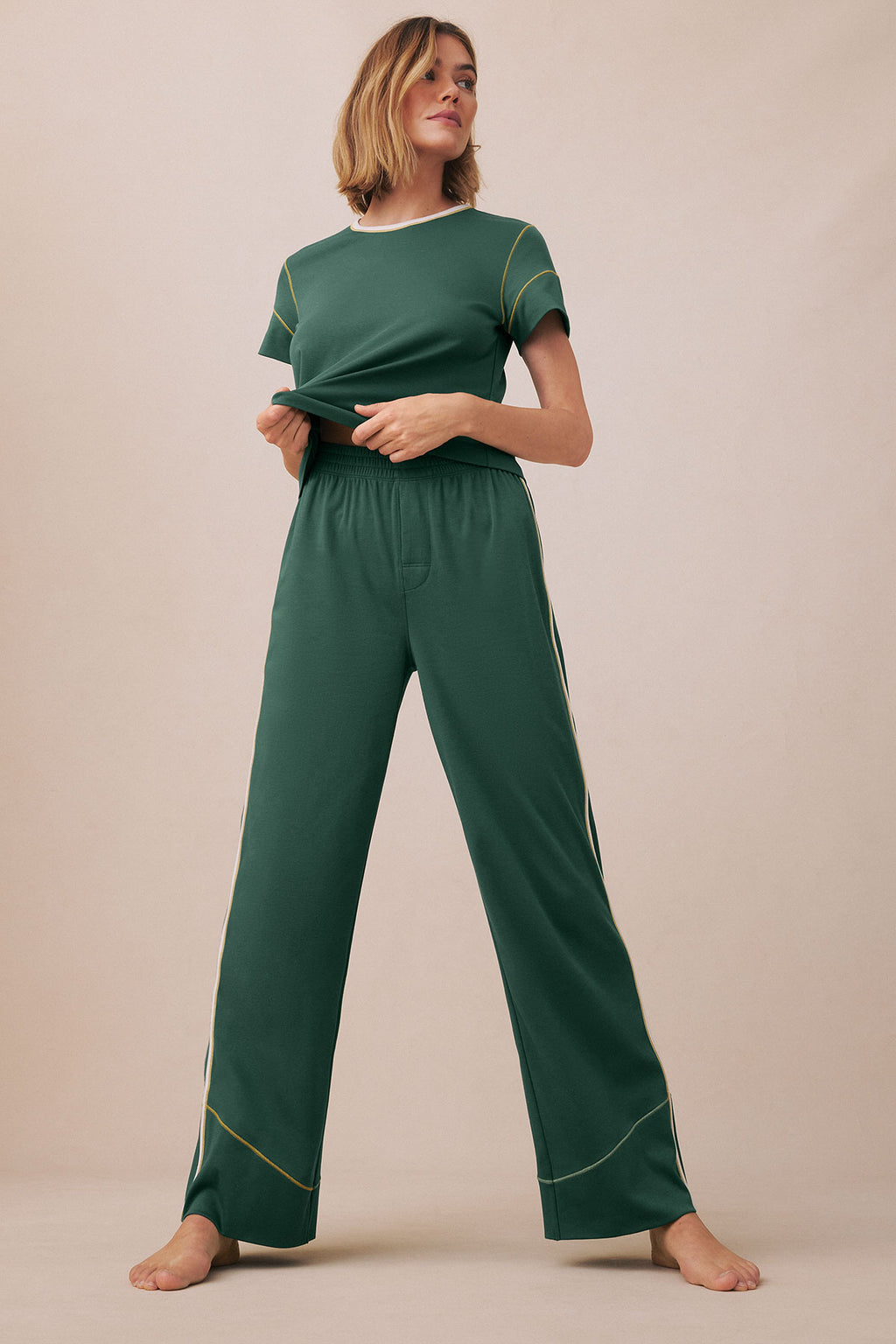 Woman wearing trekking green short-sleeve t-shirt and wide-leg pants with contrasting topstitching details.