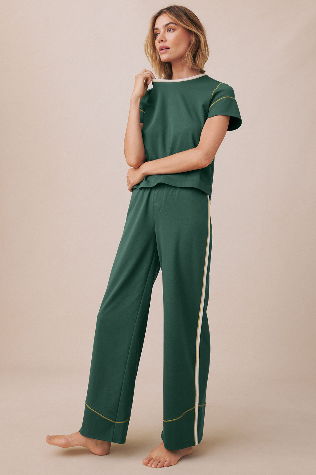 Woman wearing trekking green short-sleeve t-shirt and matching long pants with contrasting trim details.