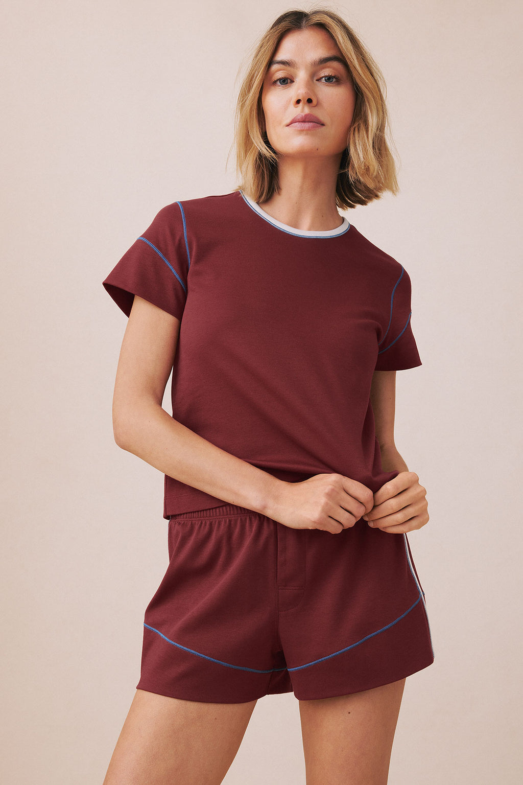 Woman wearing burgundy knit t-shirt and matching shorts with blue contrast stitching details.