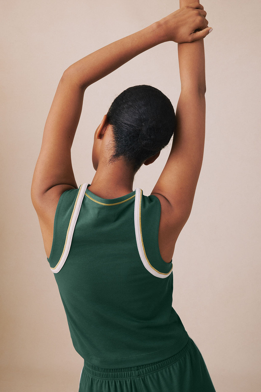 Trekking green sleeveless tank with white and yellow trim, worn with matching long pants.