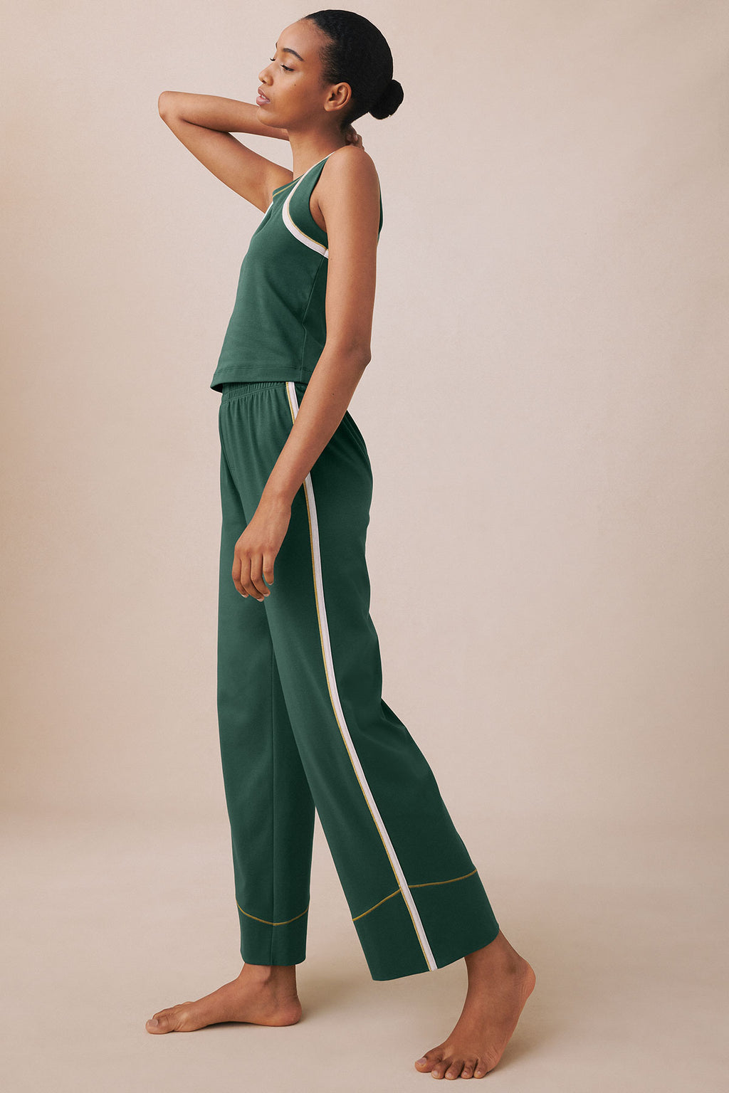 Trekking green sleeveless tank top and matching pants with white and gold trim, worn as a set.