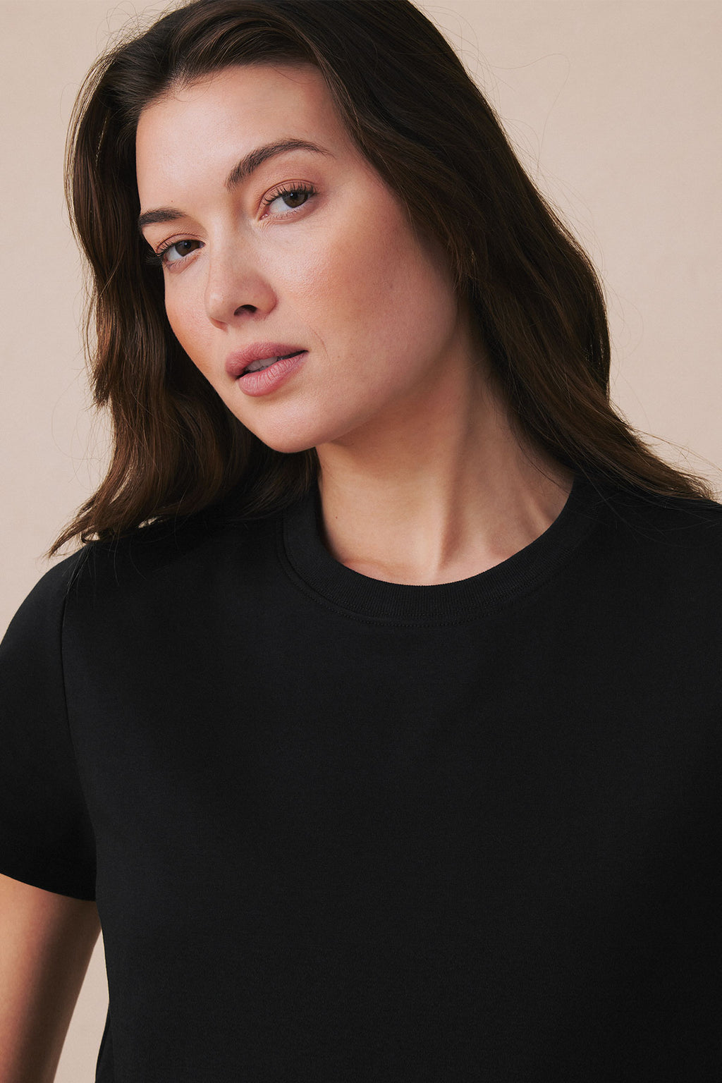 Woman wearing a black short-sleeve t-shirt with a relaxed, boxy fit and crew neckline.