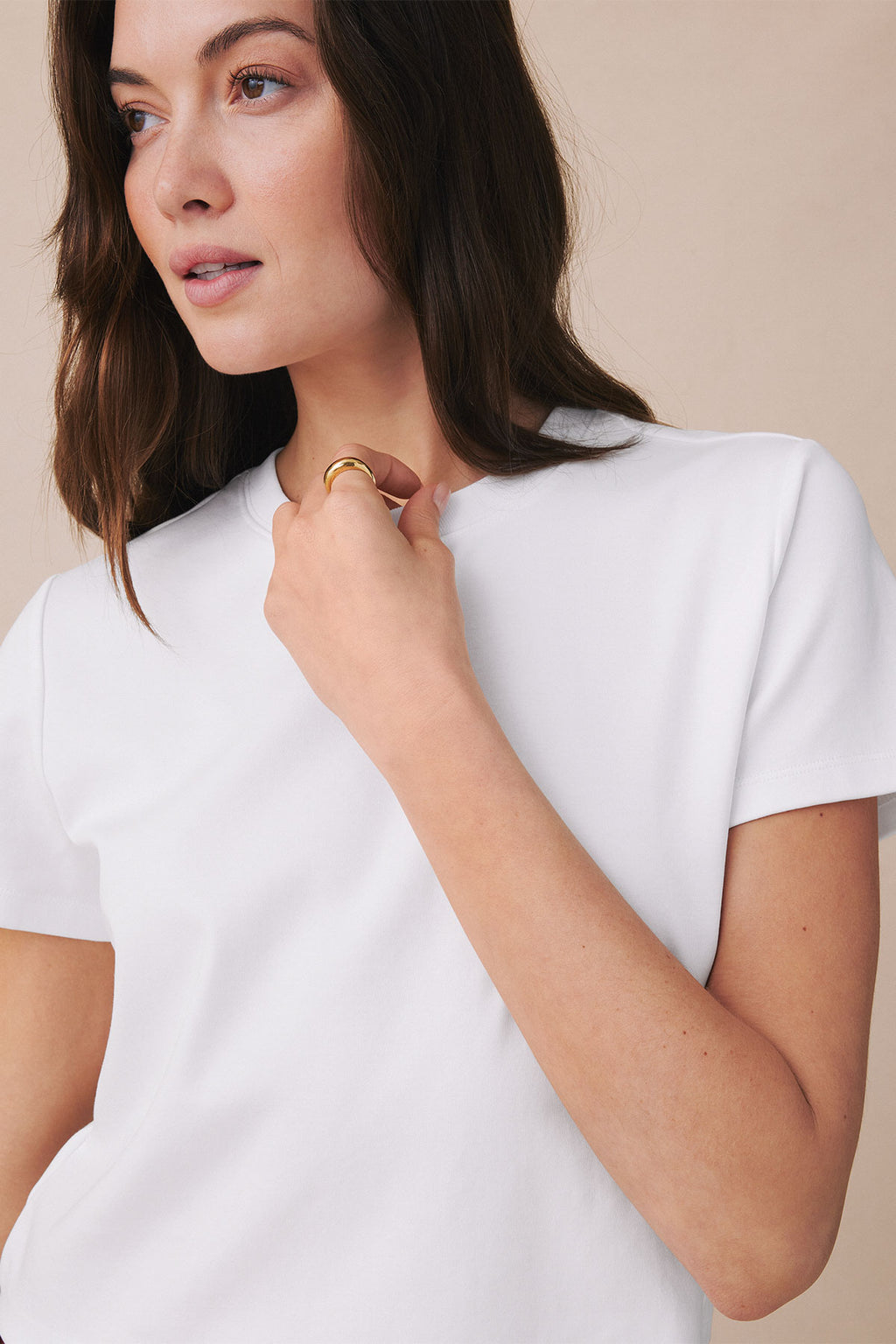 White boxy t-shirt with short sleeves and crew neckline, shown on model wearing gold ring.