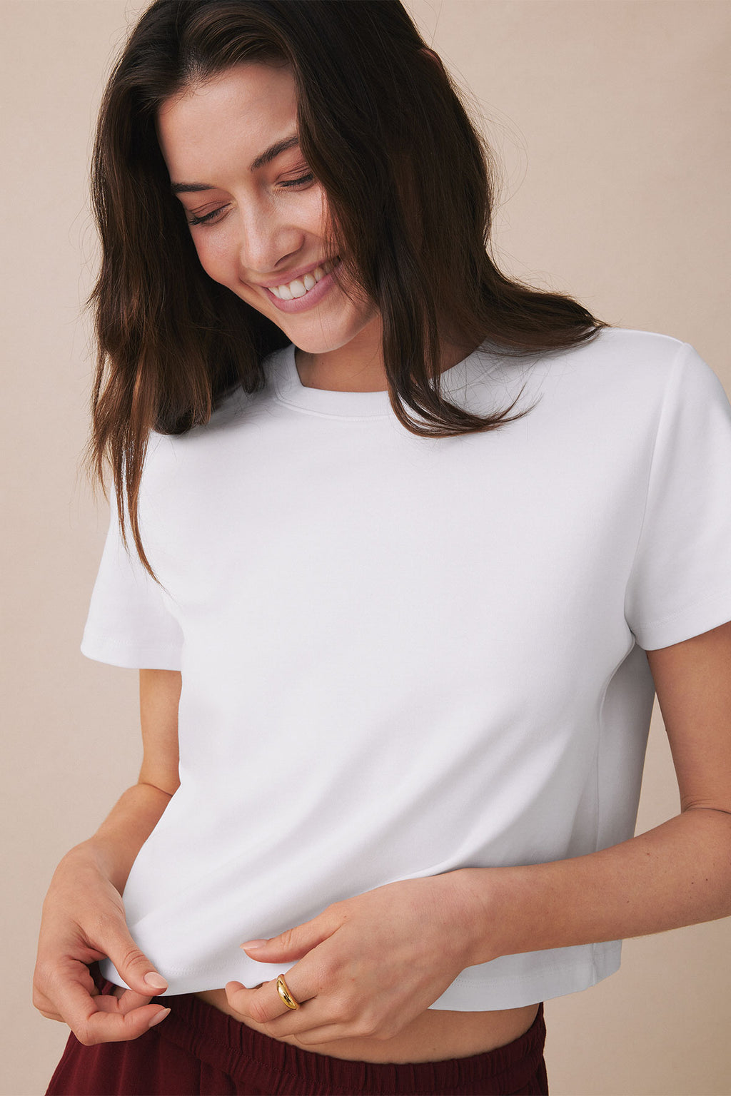 White short-sleeve boxy tee with crew neckline on model, paired with burgundy bottoms.