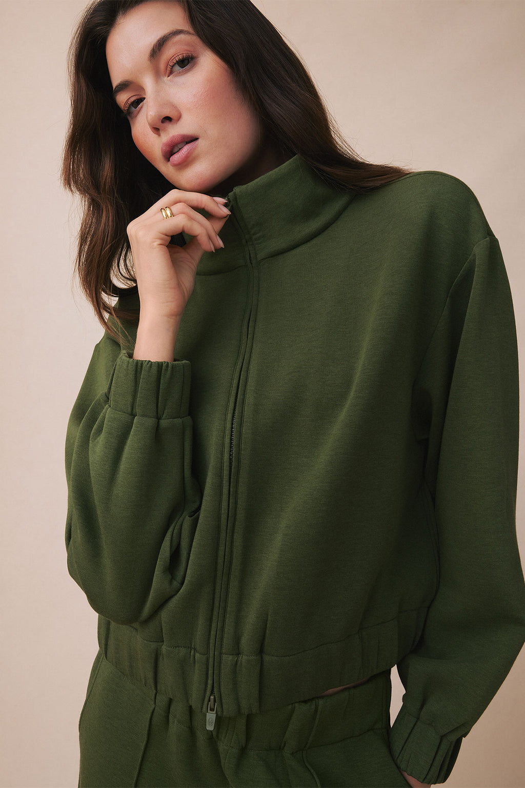 Cedar green zip-up sweatshirt with drawstring waist and side pockets on model.