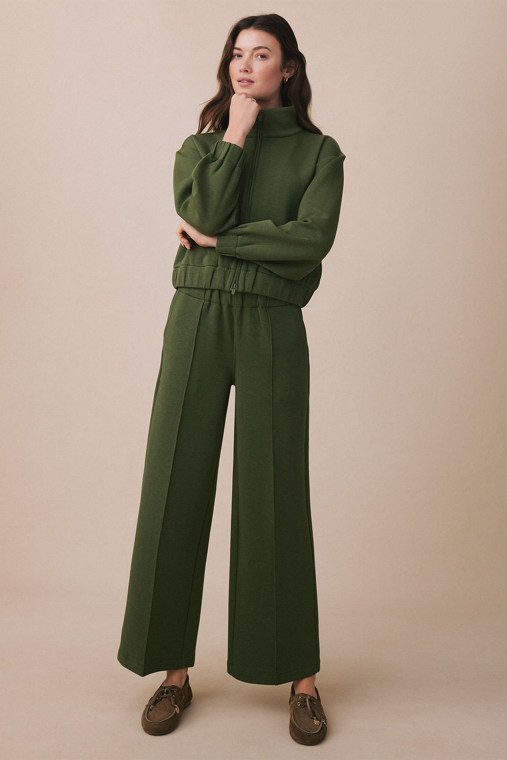 Woman wearing cedar green cropped zip-up jacket and wide-leg pants with drawstring waist.
