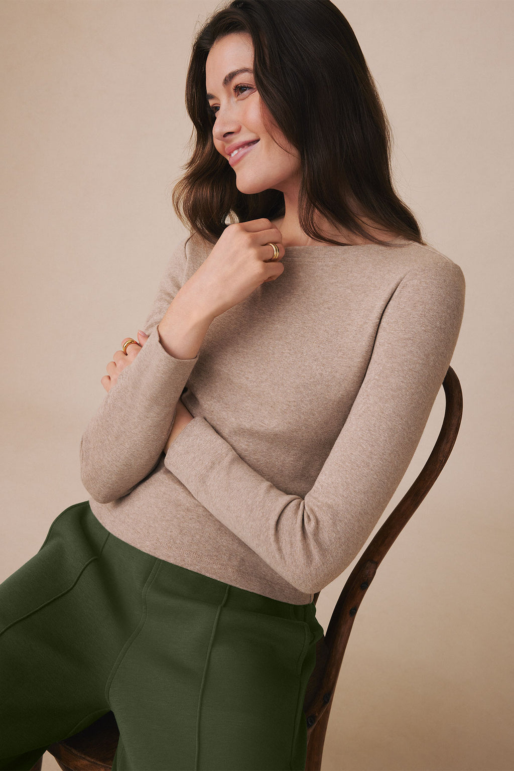 Woman wearing a fawn heather long sleeve tee with a crew neckline, styled with green pants.