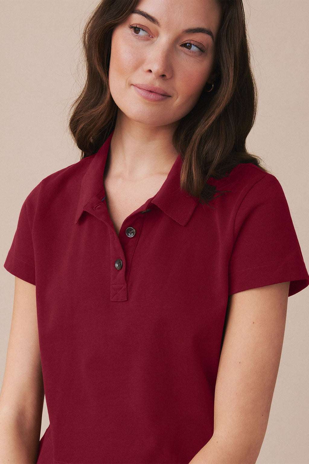 Woman wearing deep red short-sleeve collared polo shirt with button placket.