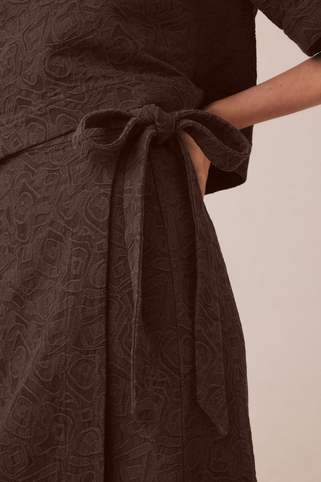 Cocoa brown jacquard popover skirt with tie waist detail and draped fabric shown on model.