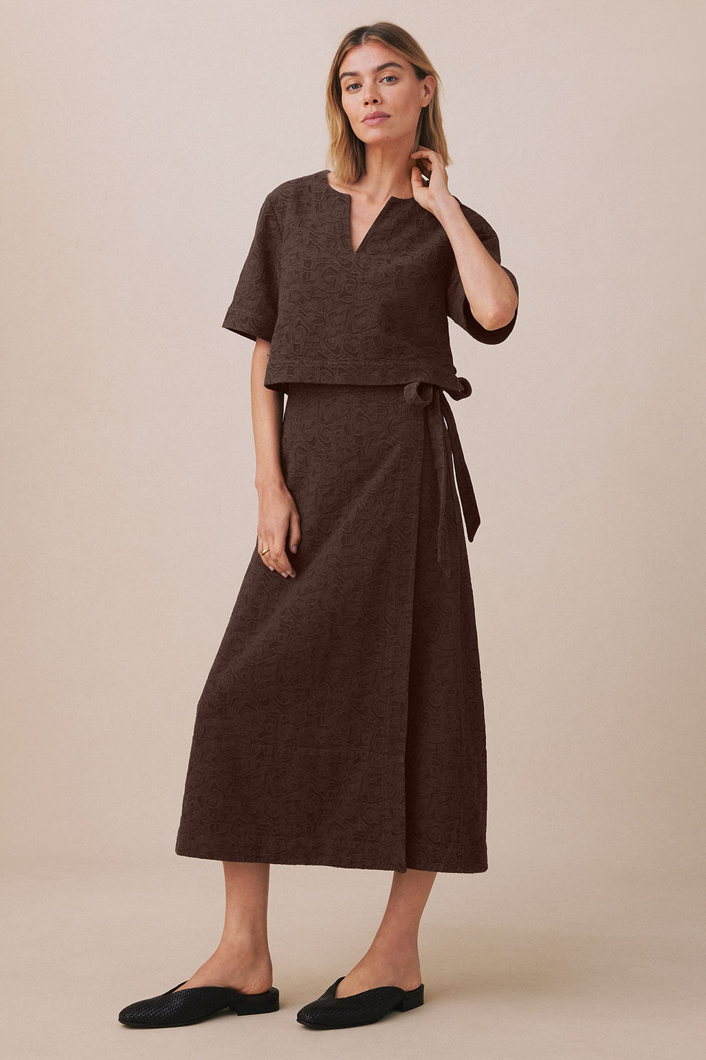 Woman wearing brown jacquard popover top and matching midi skirt with tie waist detail.