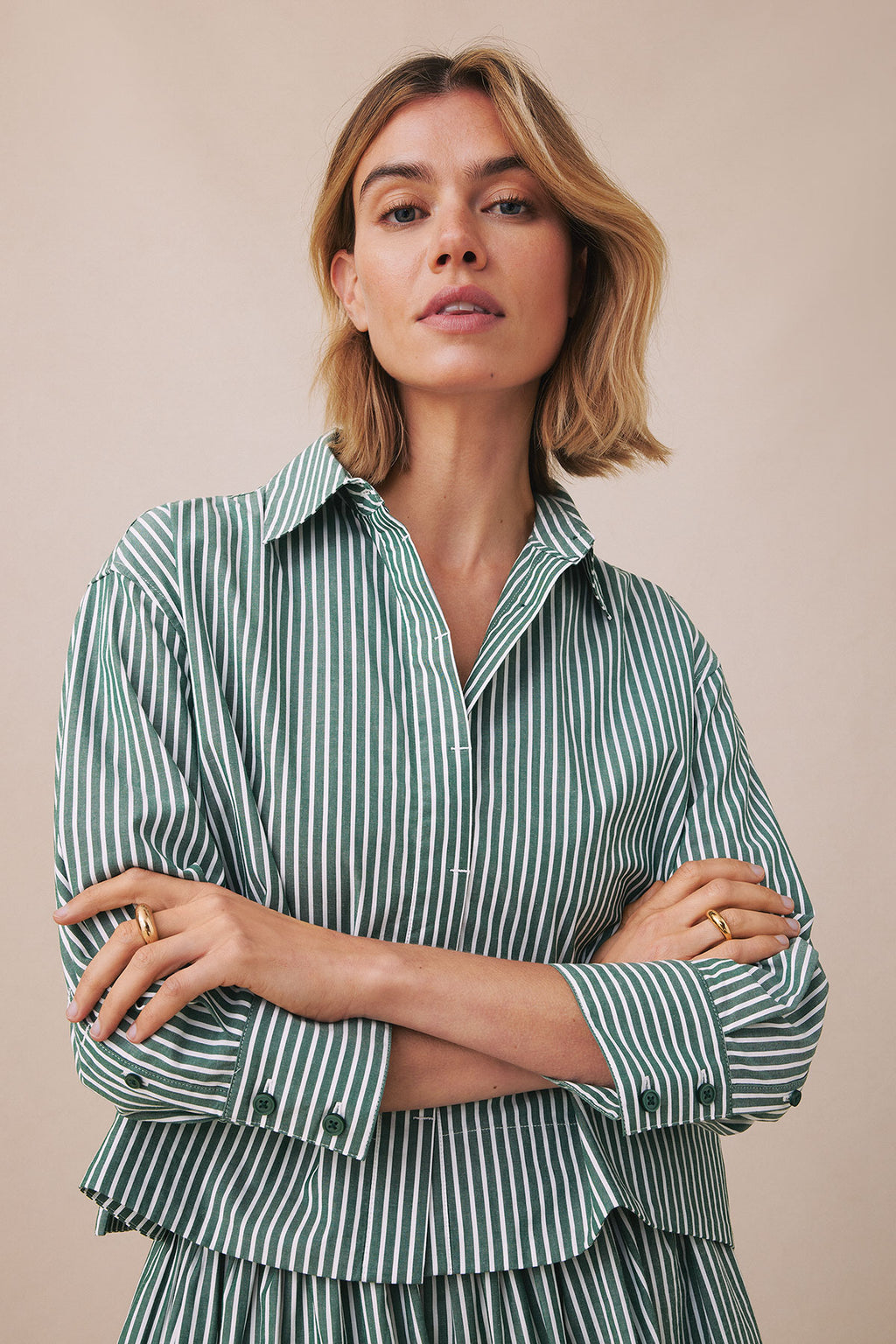 Woman wearing hunter green and white striped button-up shirt with matching striped skirt.
