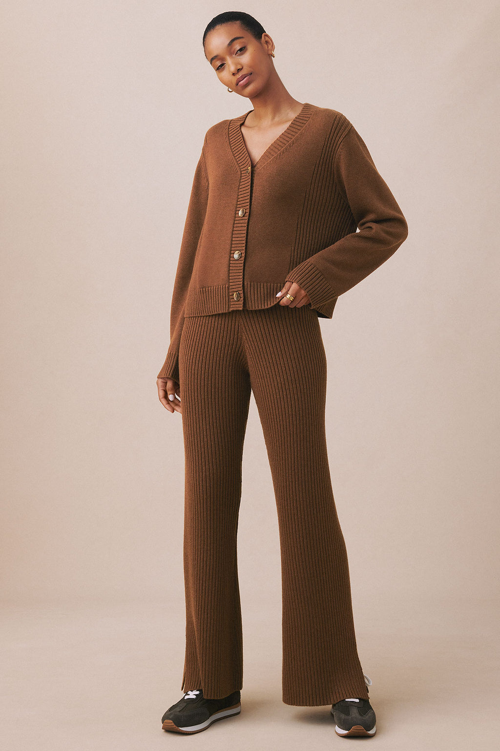 Woman wearing cinnamon ribbed cardigan with button front and matching ribbed flared pants.