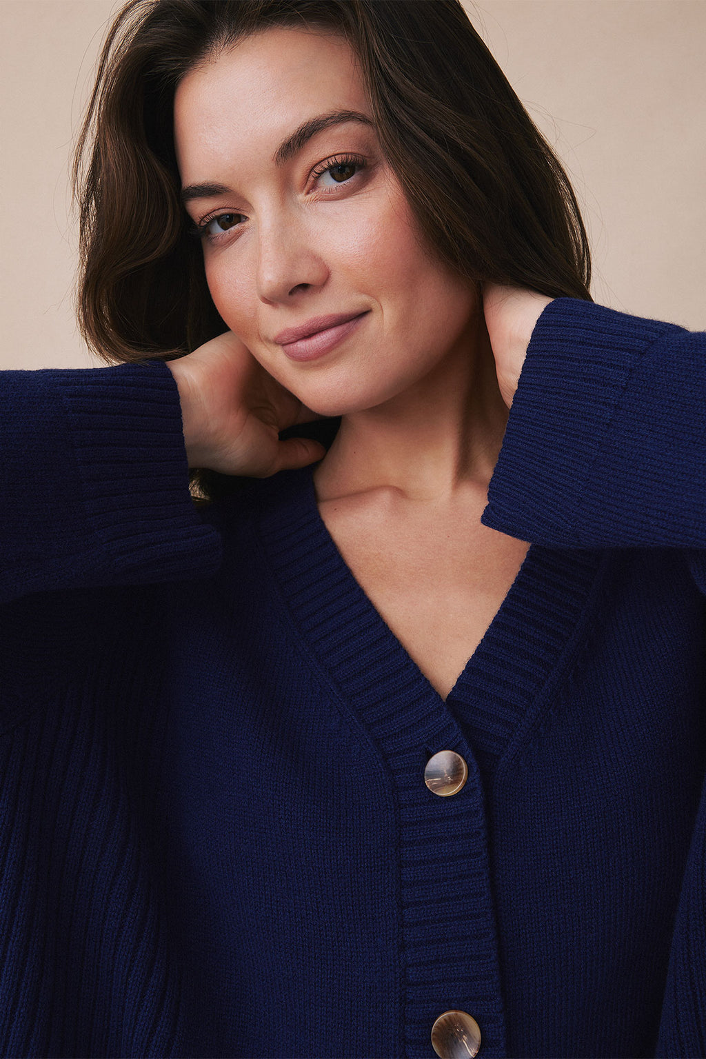 Woman wearing navy ribbed cardigan with button front and collar.