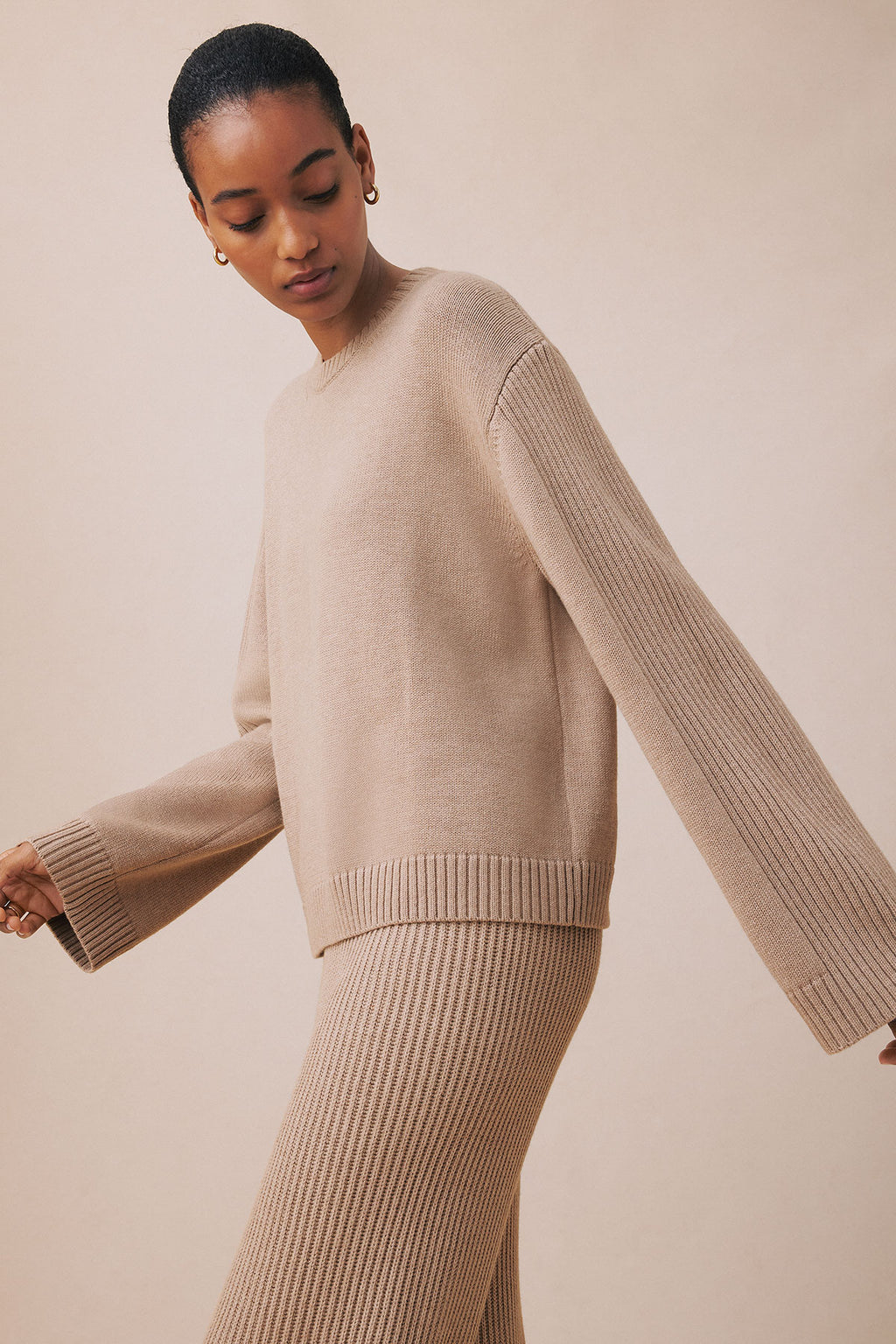 Woman wearing fawn heather ribbed knit sweater and matching ribbed jogger pants.