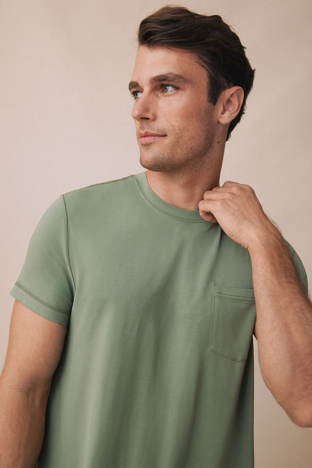 Man wearing sage green short-sleeve t-shirt with chest pocket, shown from side profile.