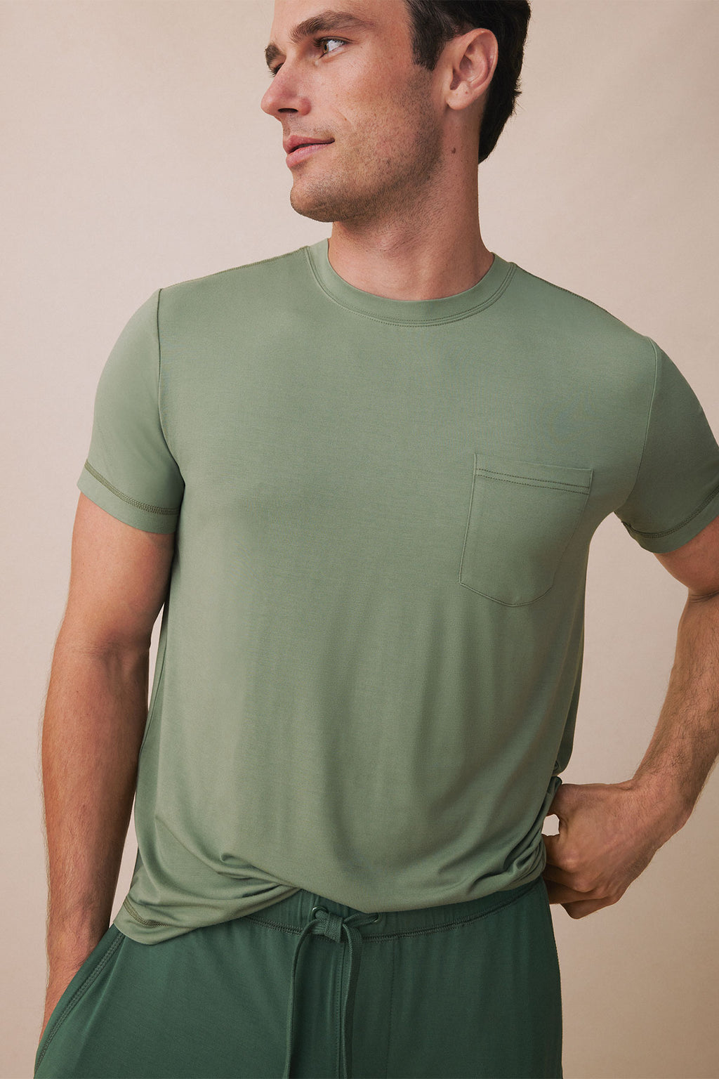 Man wearing sage green short-sleeve t-shirt with chest pocket and matching drawstring pants.