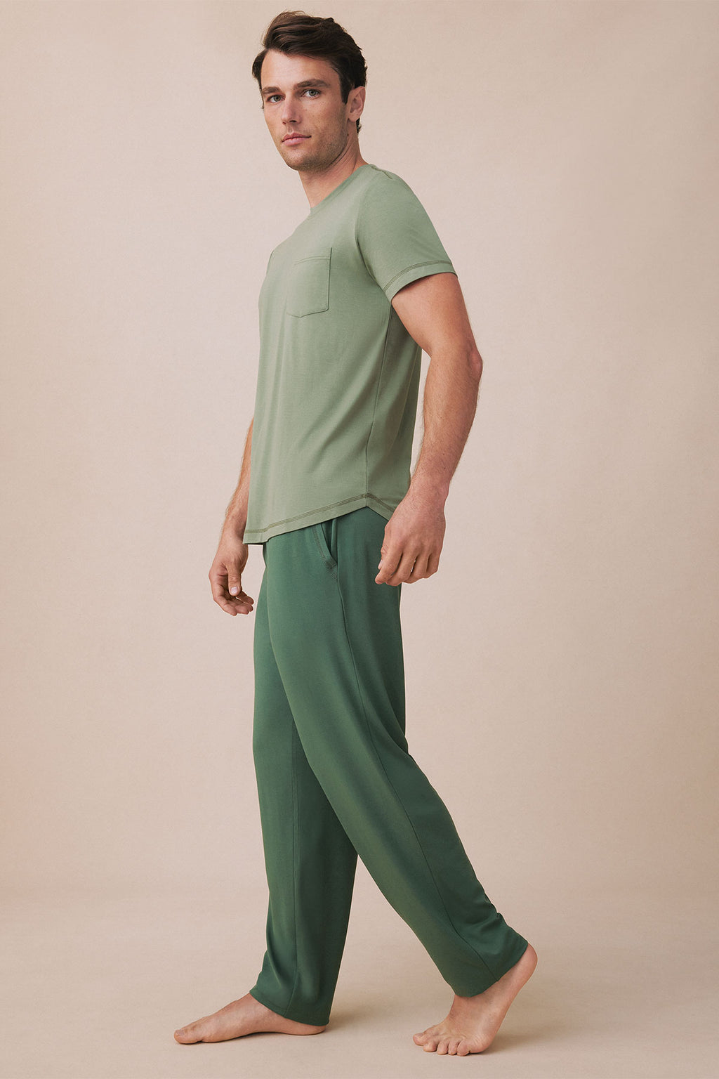 Man wearing sage green short-sleeve t-shirt with chest pocket and matching forest green pants.