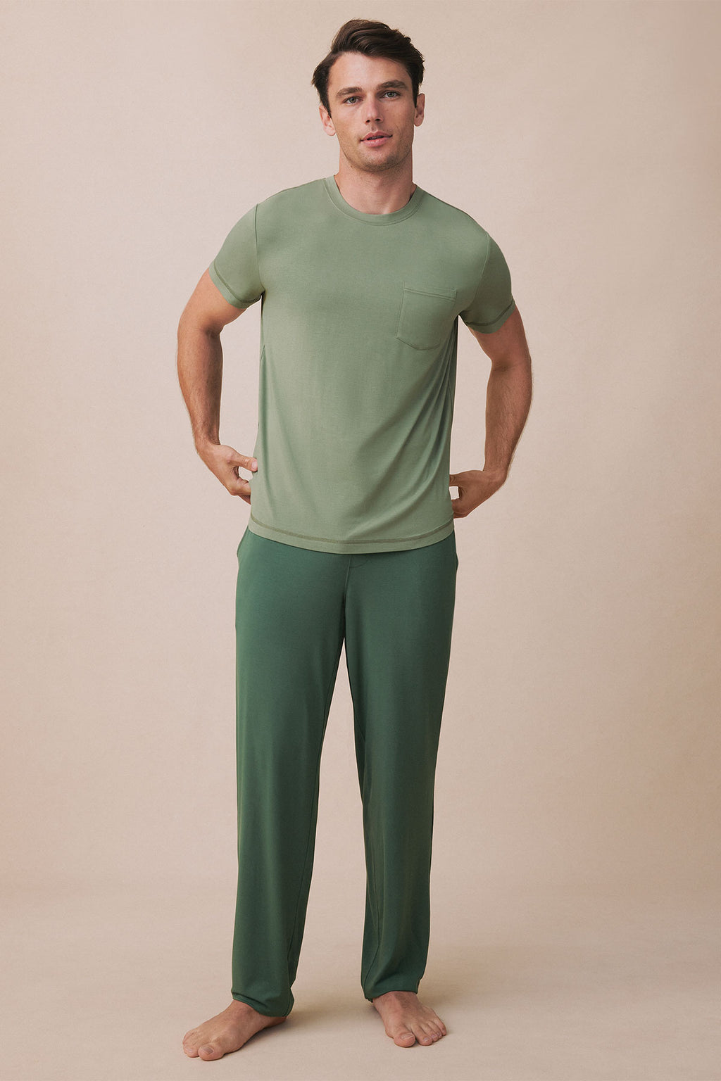 Man wearing sage green short-sleeve t-shirt with chest pocket and matching dark green pants in wildwood color.