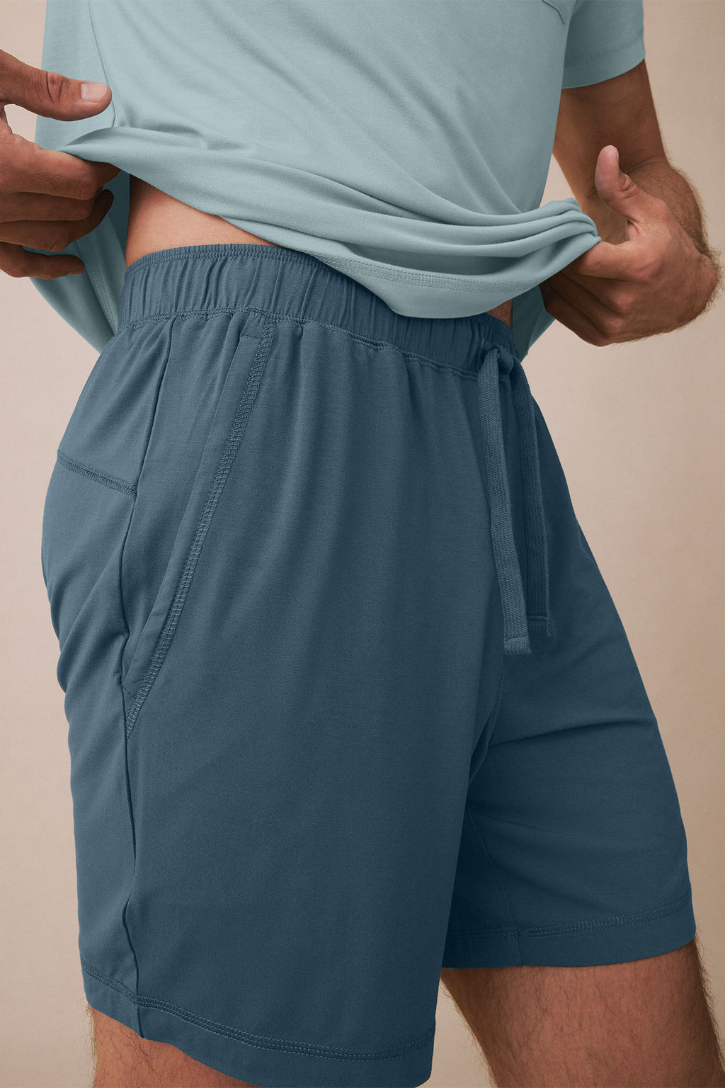 Man wearing light blue t-shirt and darker blue shorts with elastic waistband and side pockets.